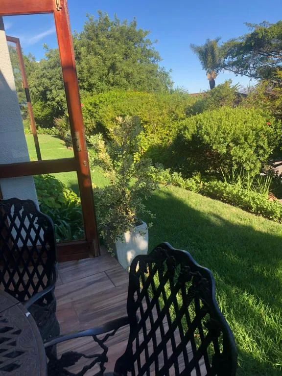 Outdoor seating area with black chairs overlooking lush green gardens and trees