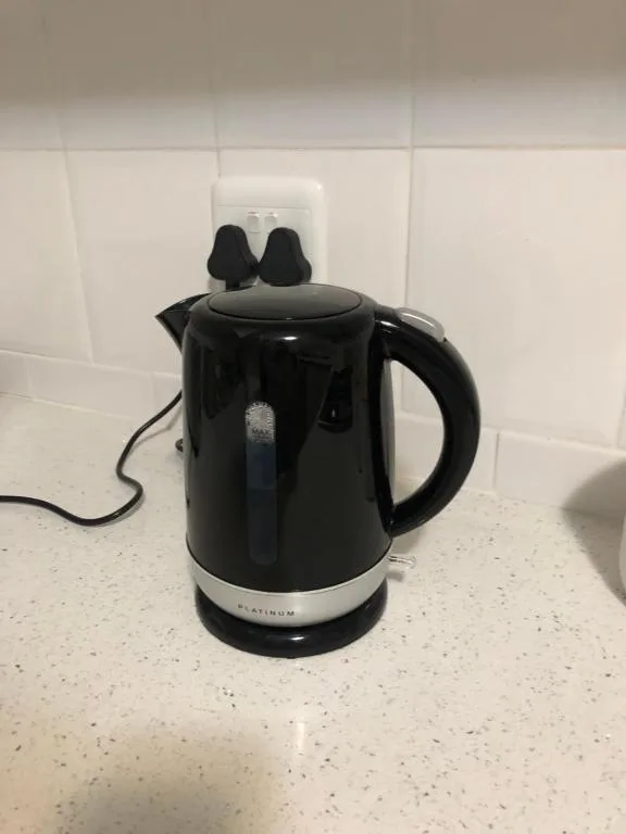 Black electric kettle on kitchen counter with white subway tiles