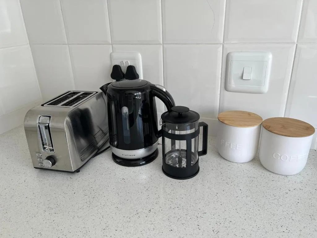Kitchen countertop with toaster, kettle, coffee press, and storage containers