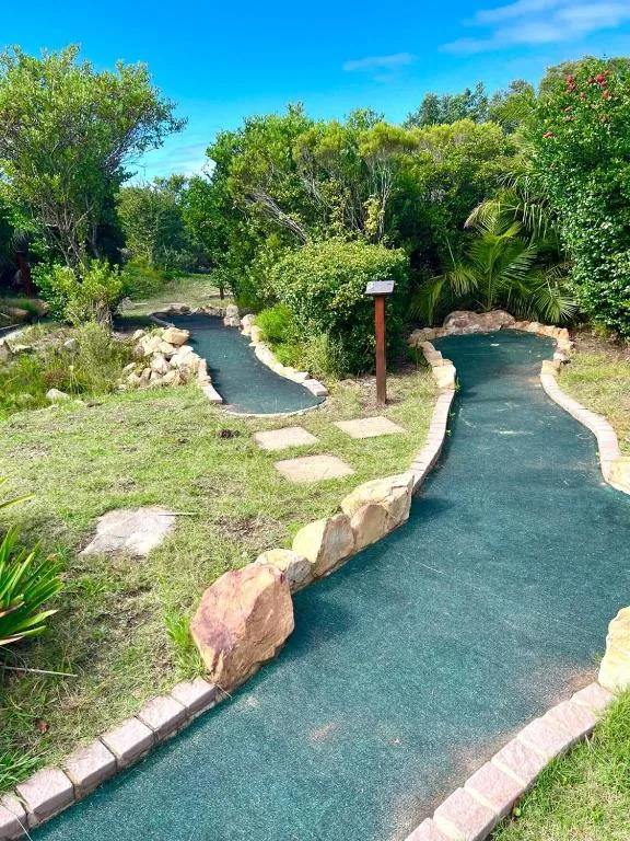 Miniature golf course with winding turquoise path and lush garden surroundings