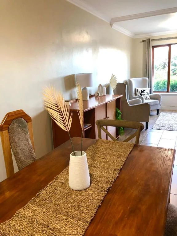 Wooden dining table with woven runner and fresh floral arrangement indoors