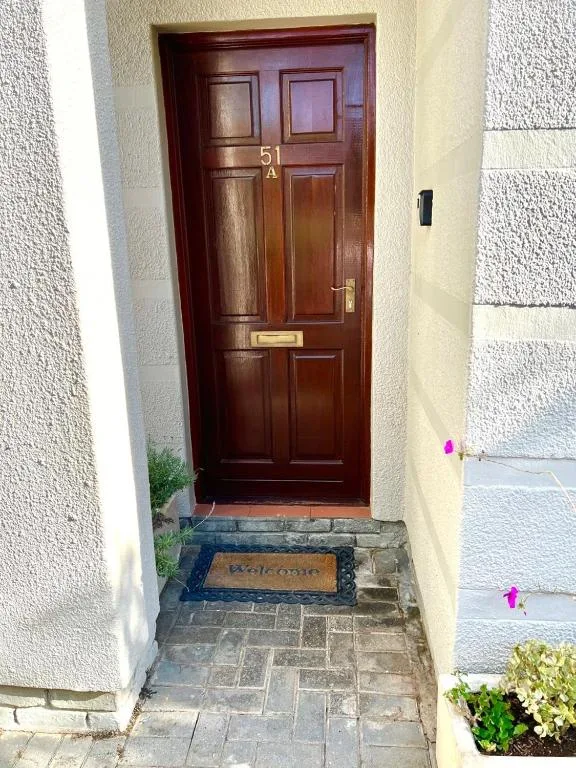 Dark red front door entrance with welcome mat and stone pathway