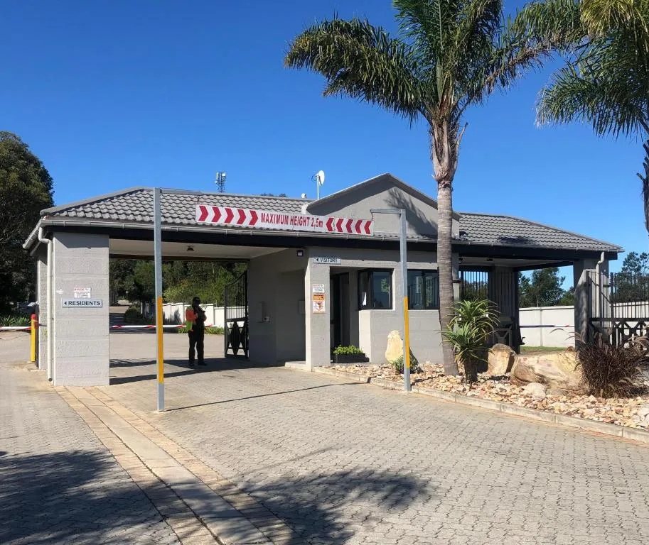Modern apartment entrance with covered carport and palm trees, clear blue sky