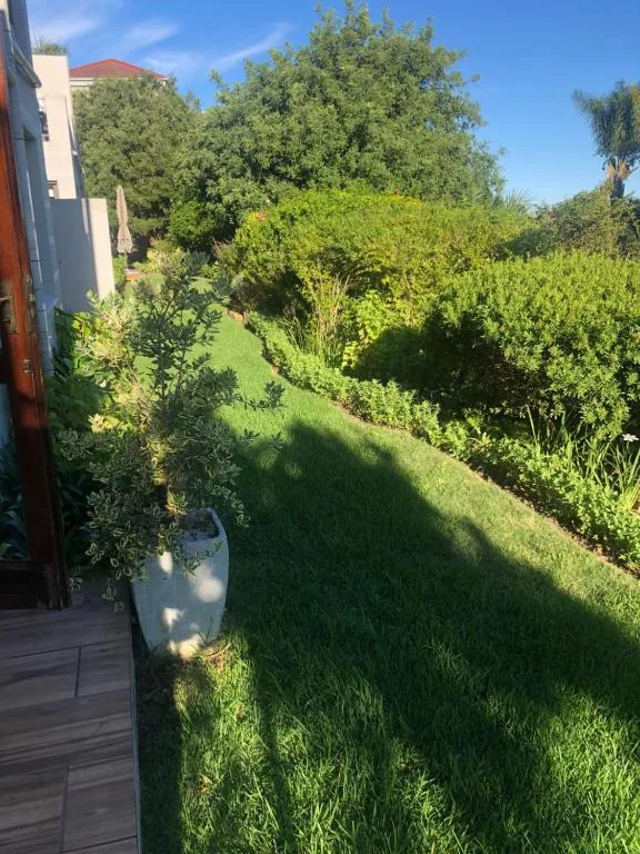 Lush green garden with mature trees and manicured lawn beside property