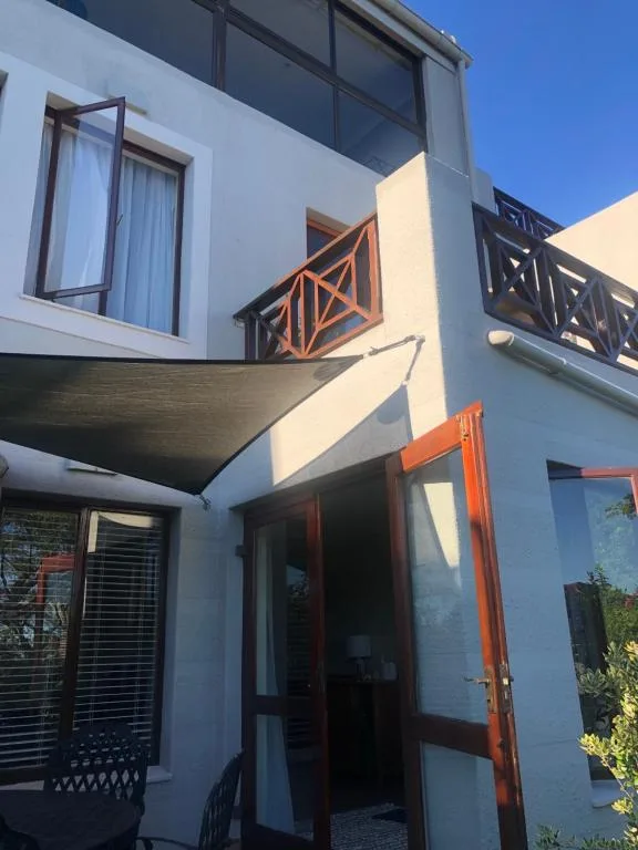 Modern white apartment building with wooden deck railings and orange accents