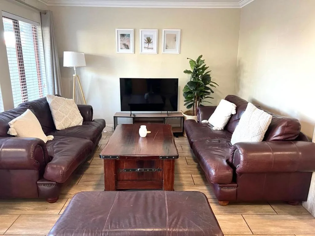 Spacious living room with burgundy leather sofas and flat-screen television