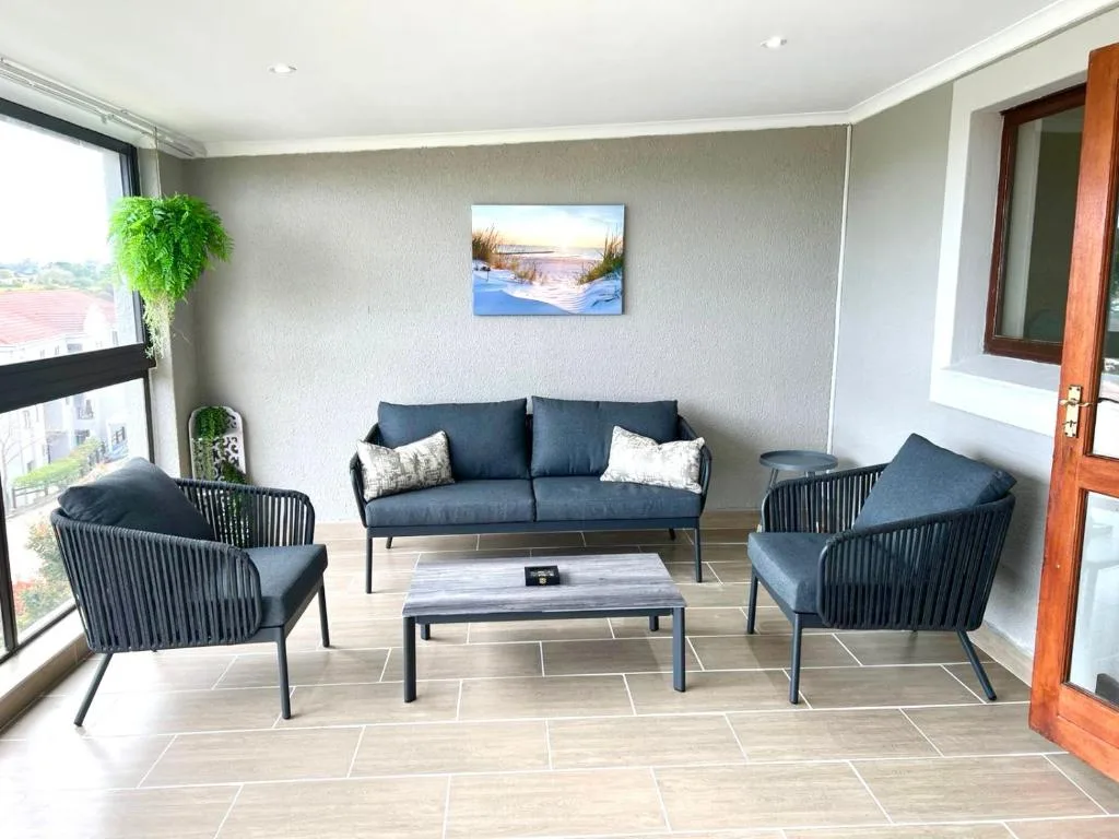 Modern lounge with dark sofa and armchairs, wooden doors, large windows