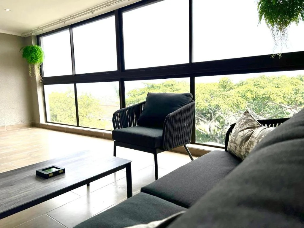 Modern lounge with black seating and floor-to-ceiling windows overlooking trees