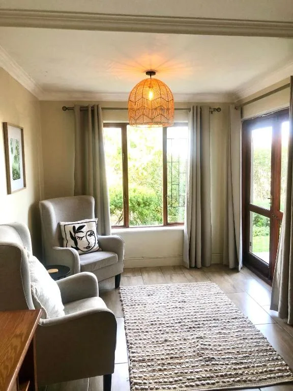 Bright lounge with comfortable armchairs, woven pendant light, garden views through doors