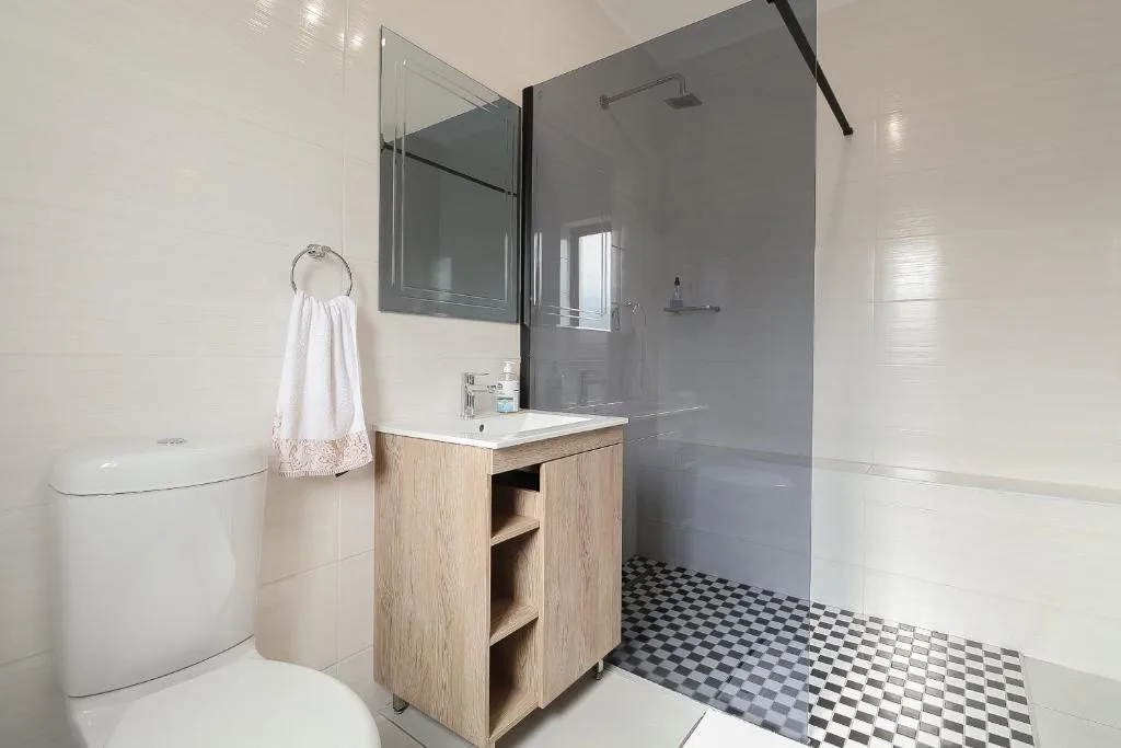 Modern bathroom with wooden vanity, rainfall shower, and geometric floor tiles