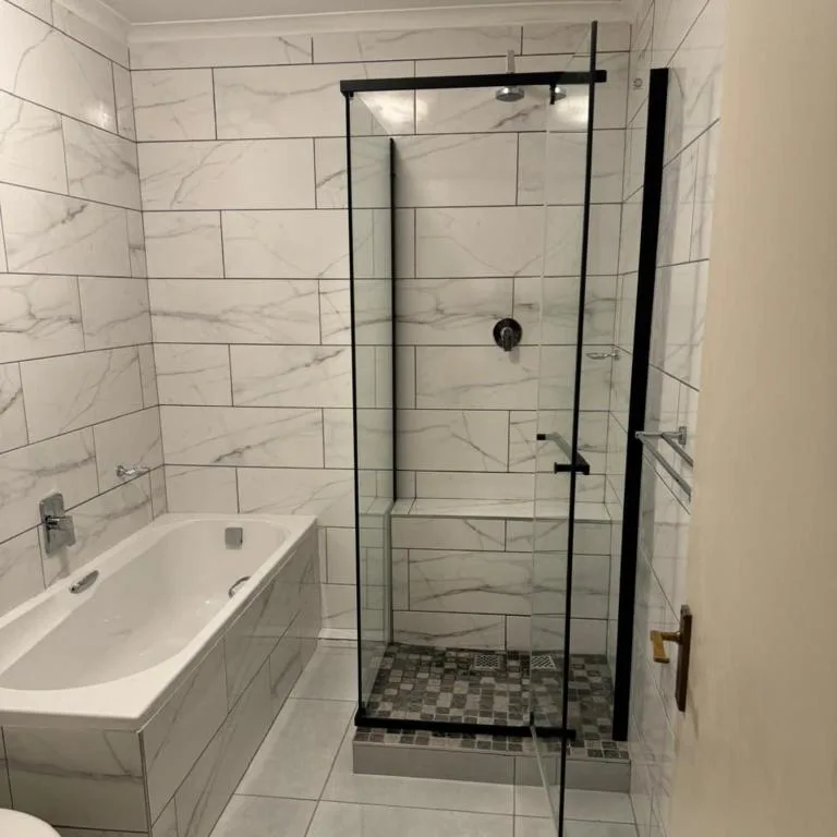 Modern bathroom with marble tiles, soaking tub, and glass shower enclosure