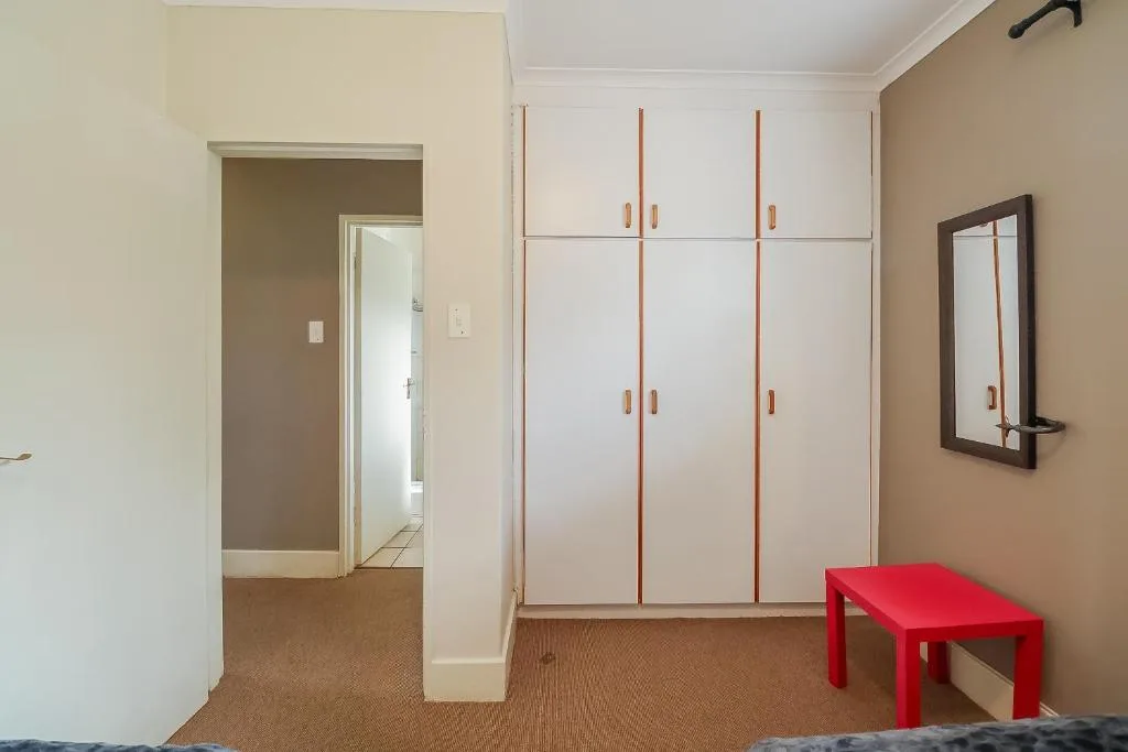 Spacious bedroom with built-in white wardrobes and red bench seating