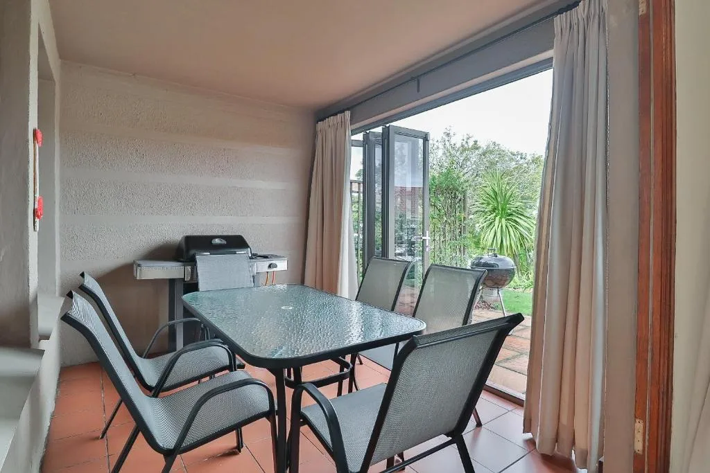 Covered patio with dining table and chairs overlooking garden