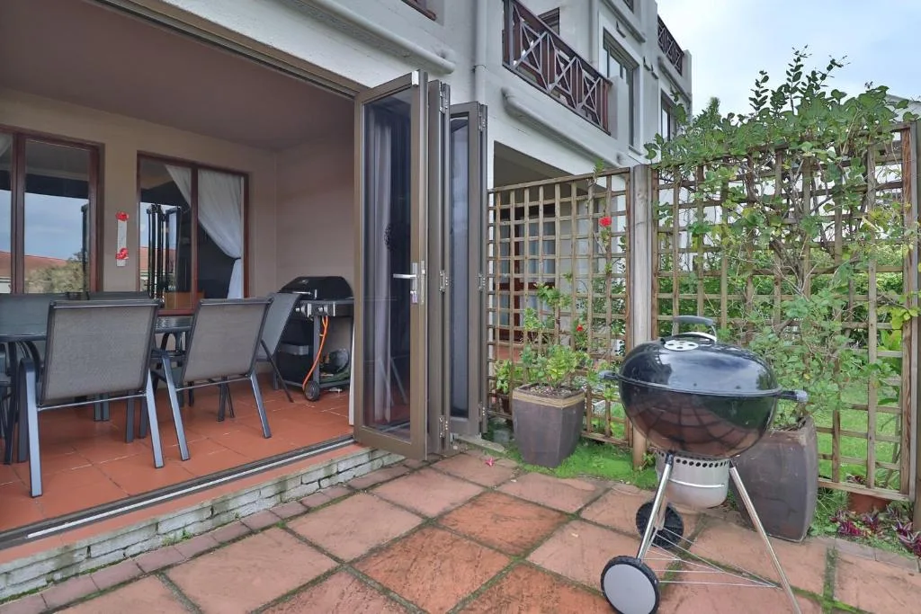 Outdoor patio with braai grill, seating, and garden trellis