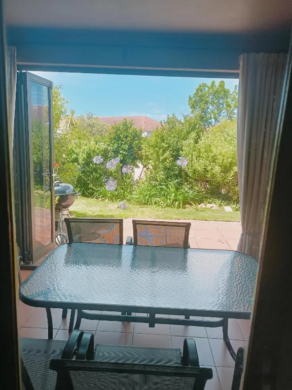 Outdoor patio with dining table overlooking lush garden and neighboring properties