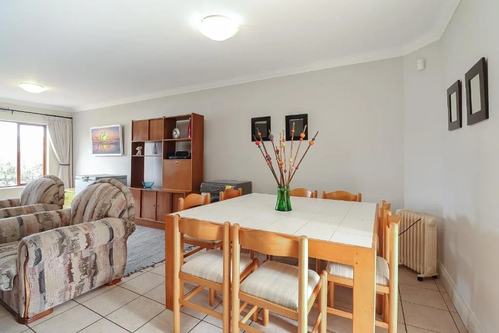 Open-plan dining and lounge area with wooden table and striped armchairs