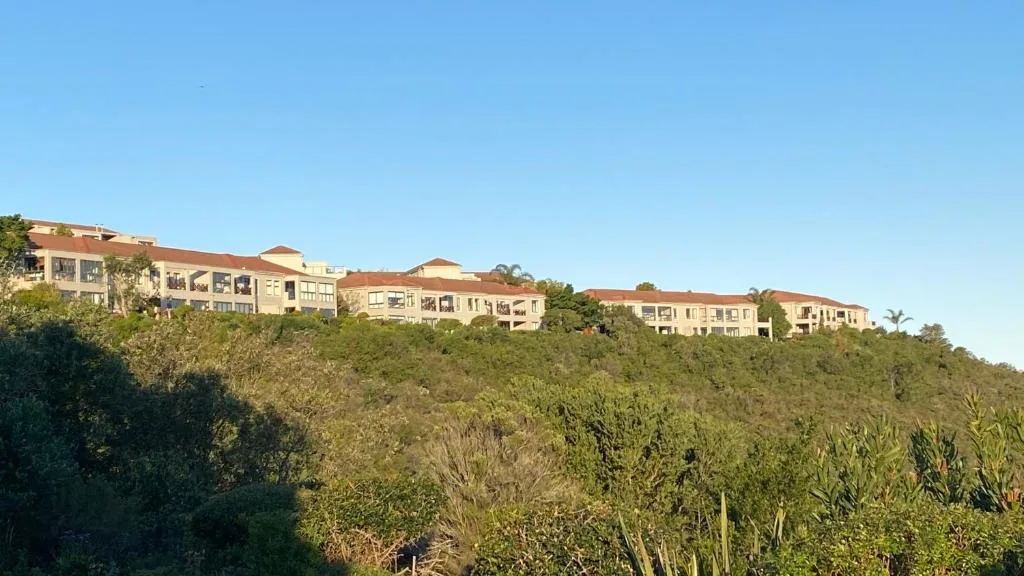 Hillside residential complex with terracotta roofs overlooking lush green vegetation