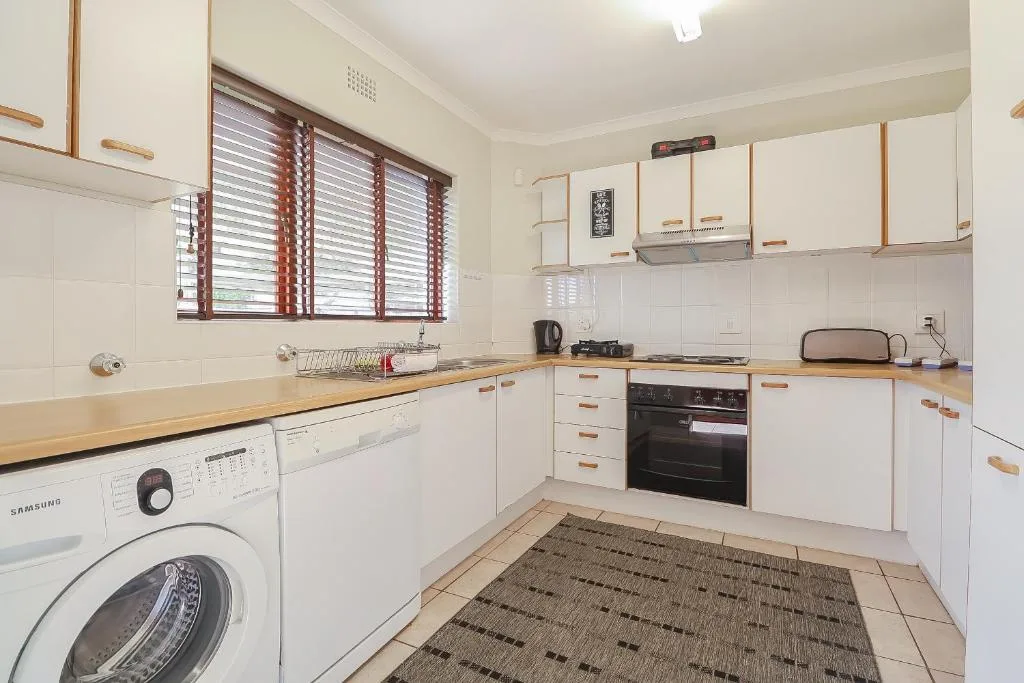 Bright white kitchen with wooden countertops, oven, and washing machine