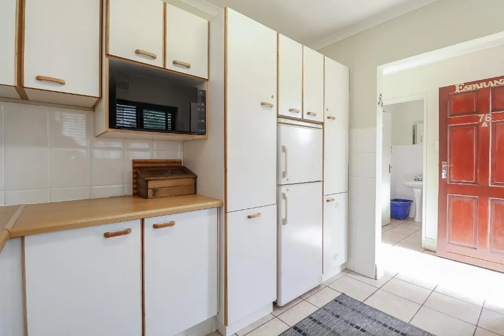 White kitchen with wooden countertop, refrigerator, and microwave oven