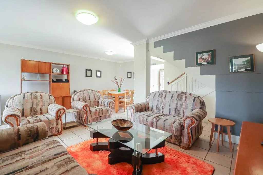 Spacious living room with patterned sofas, glass coffee table, and orange accents