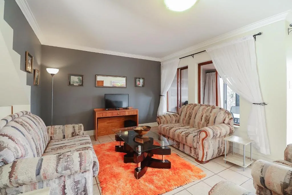 Spacious lounge with patterned sofas, TV, and orange accent rug