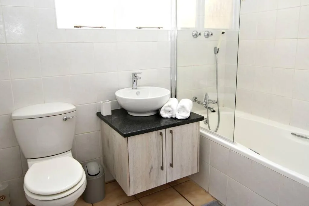 Modern bathroom with toilet, round vessel sink, and glass shower enclosure