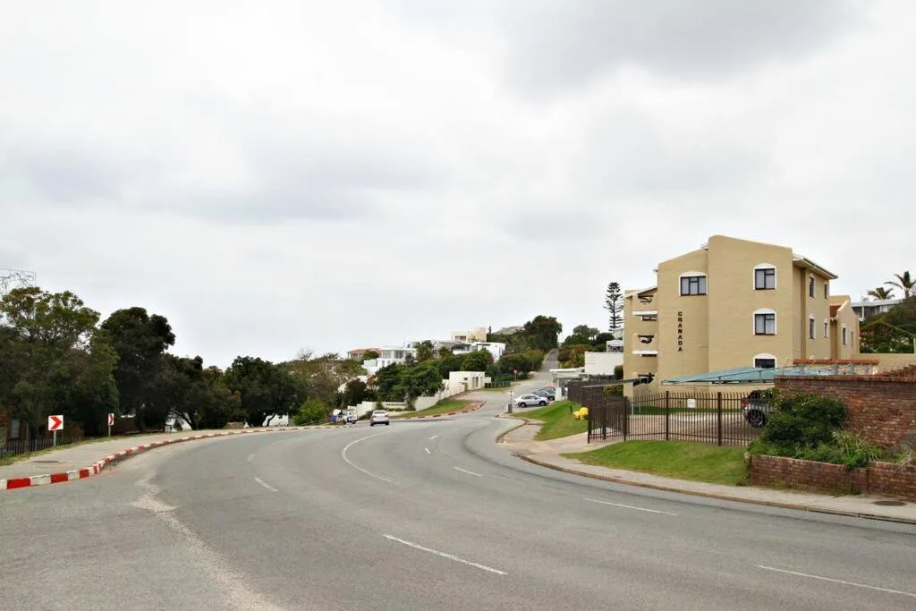 Yellow apartment building with secure parking and gated entrance on hillside street