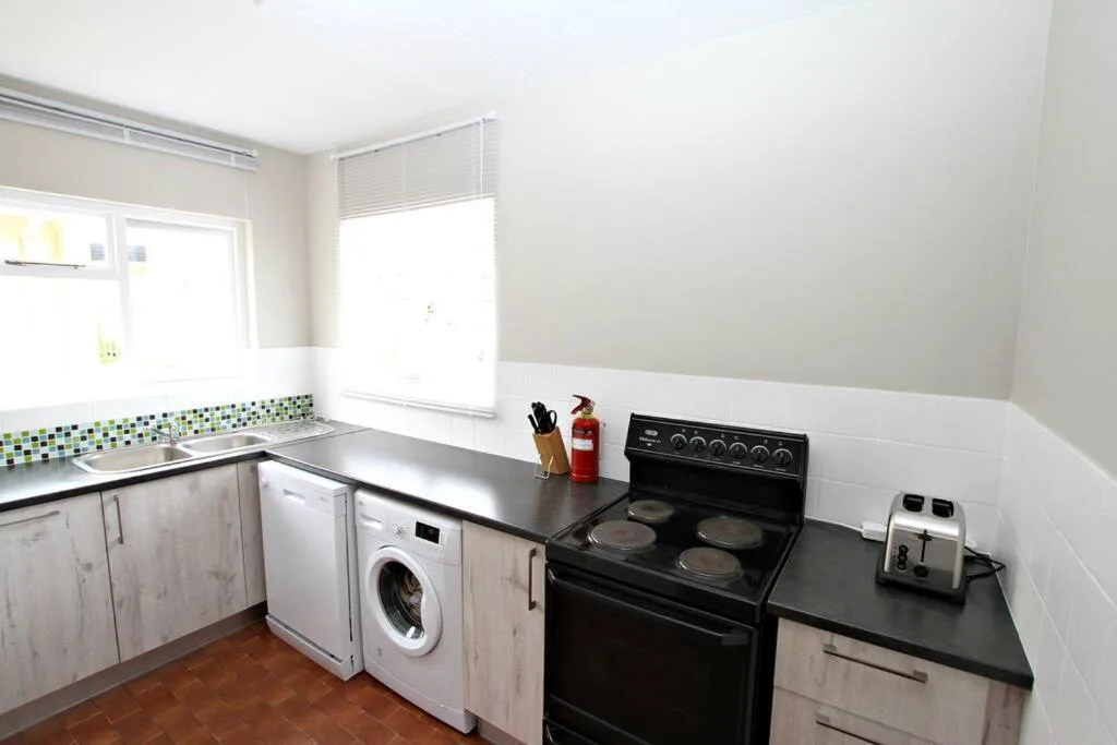 Modern kitchen with black electric stove, washing machine, and mosaic backsplash