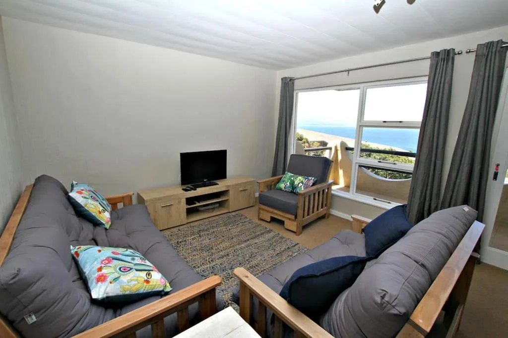 Spacious lounge with gray sofas, TV, and ocean view through large windows