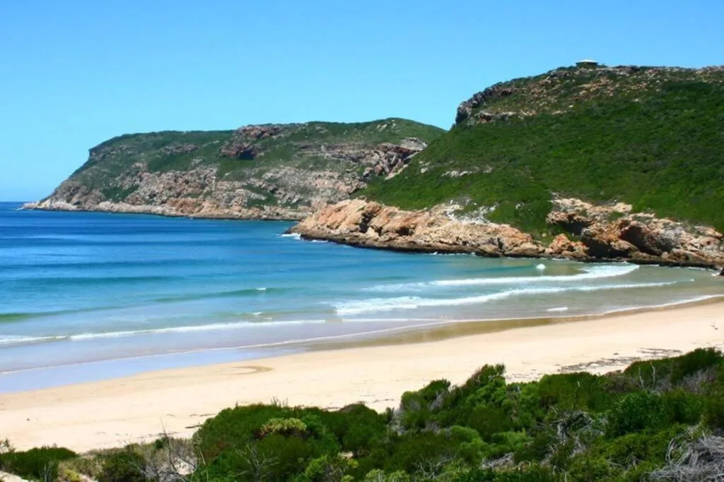 Pristine beach with turquoise waters and rocky cliffs under clear sky