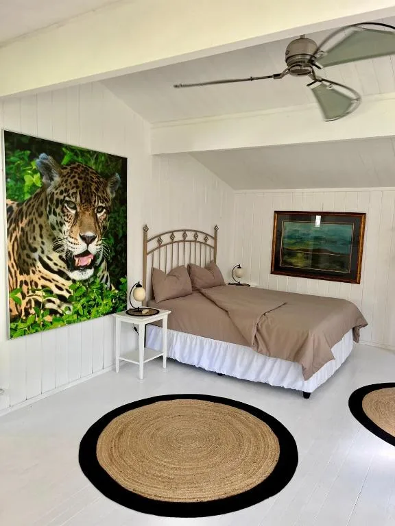 Bright bedroom with queen bed, leopard artwork, and woven circular rugs