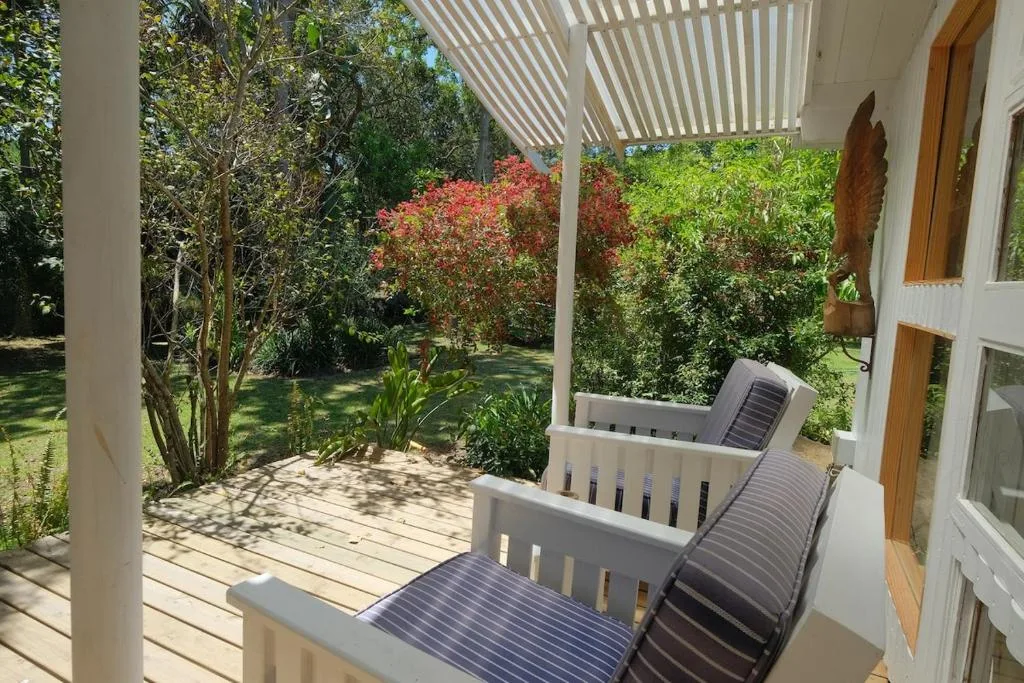 Covered patio with loungers overlooking lush garden with blooming flowers