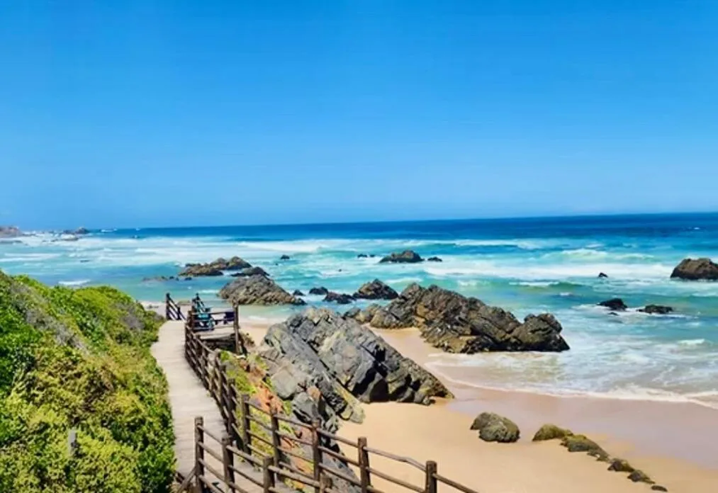 Scenic coastal view with rocky outcrops, pristine beach, and turquoise ocean waters