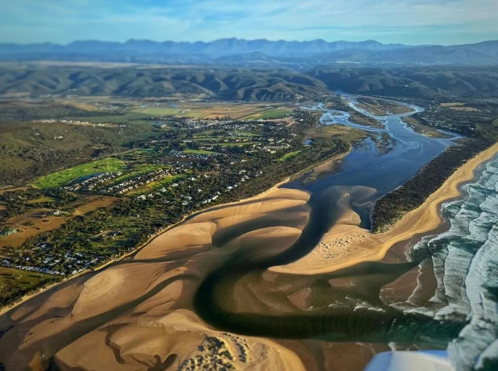 Aerial view of Piesang Valley with river, beach, and mountains beyond
