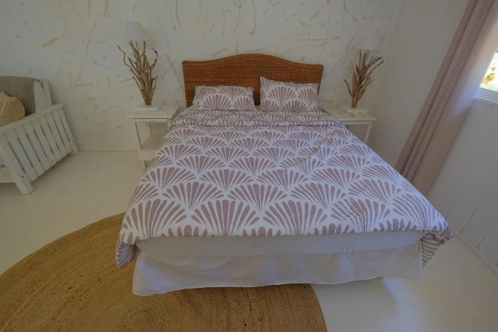 Bedroom with patterned purple bedding and woven rattan headboard