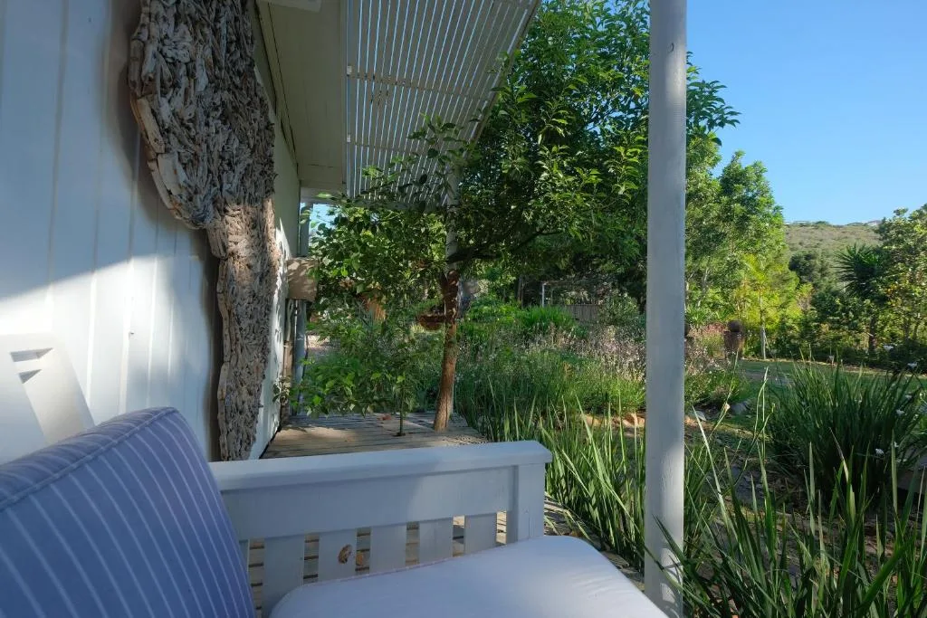 Covered patio with white railings overlooking lush garden and distant hills
