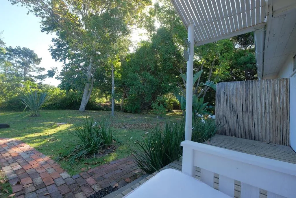 Wooden deck with white railings overlooking lush garden and trees