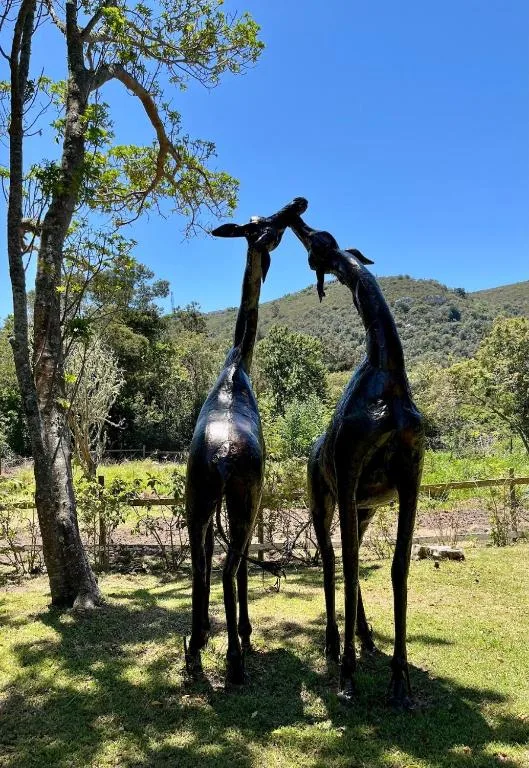 Black metal giraffe sculpture in garden with mountain views