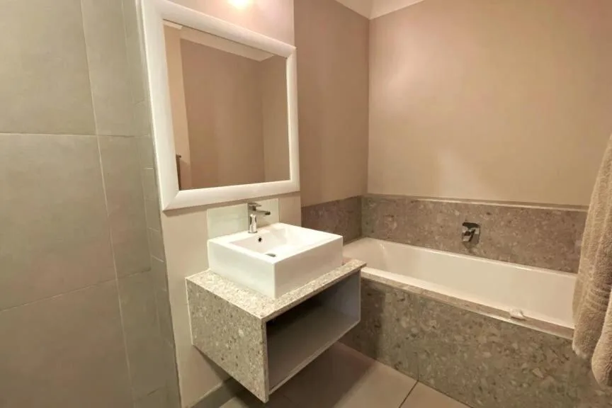 Modern bathroom with vessel sink, illuminated mirror, and bathtub