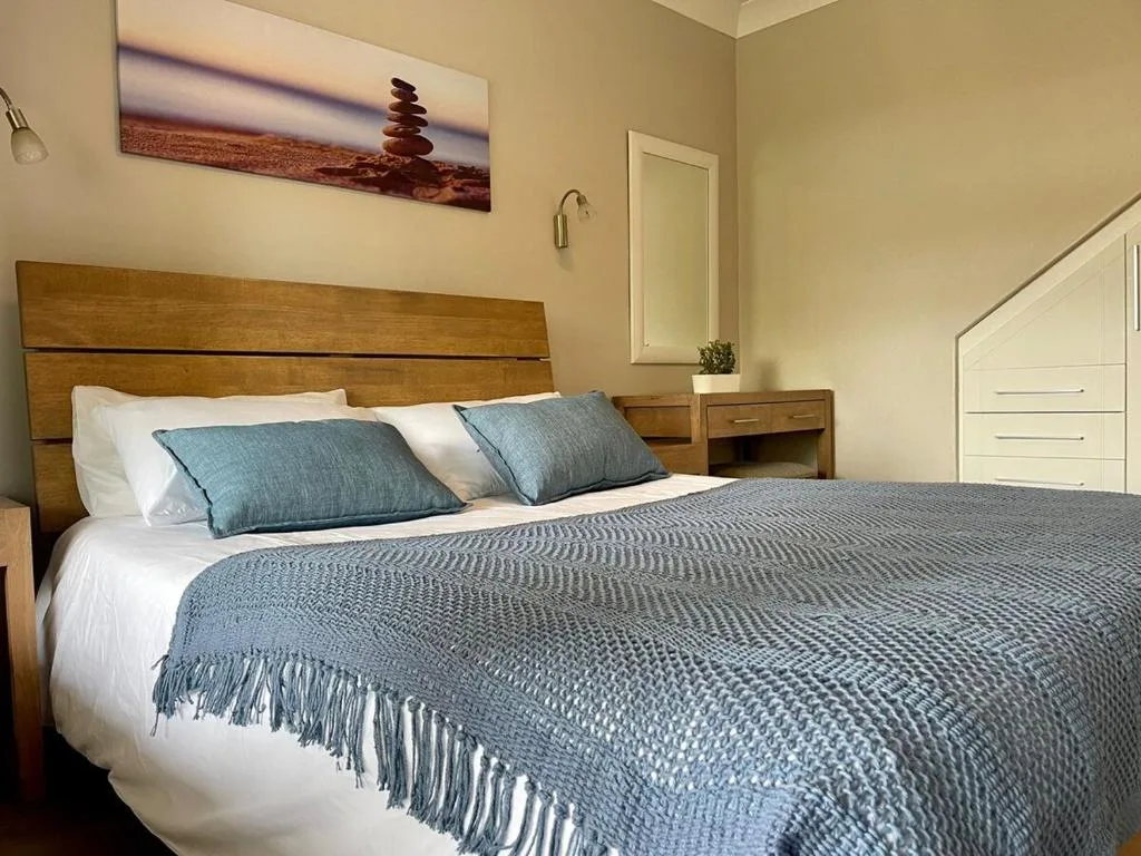 Spacious bedroom with wooden headboard and blue bedding