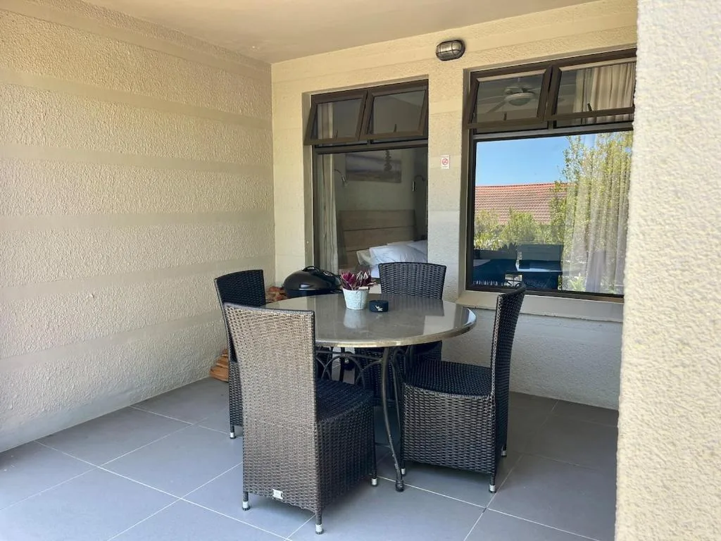 Covered patio with round table and wicker chairs overlooking garden