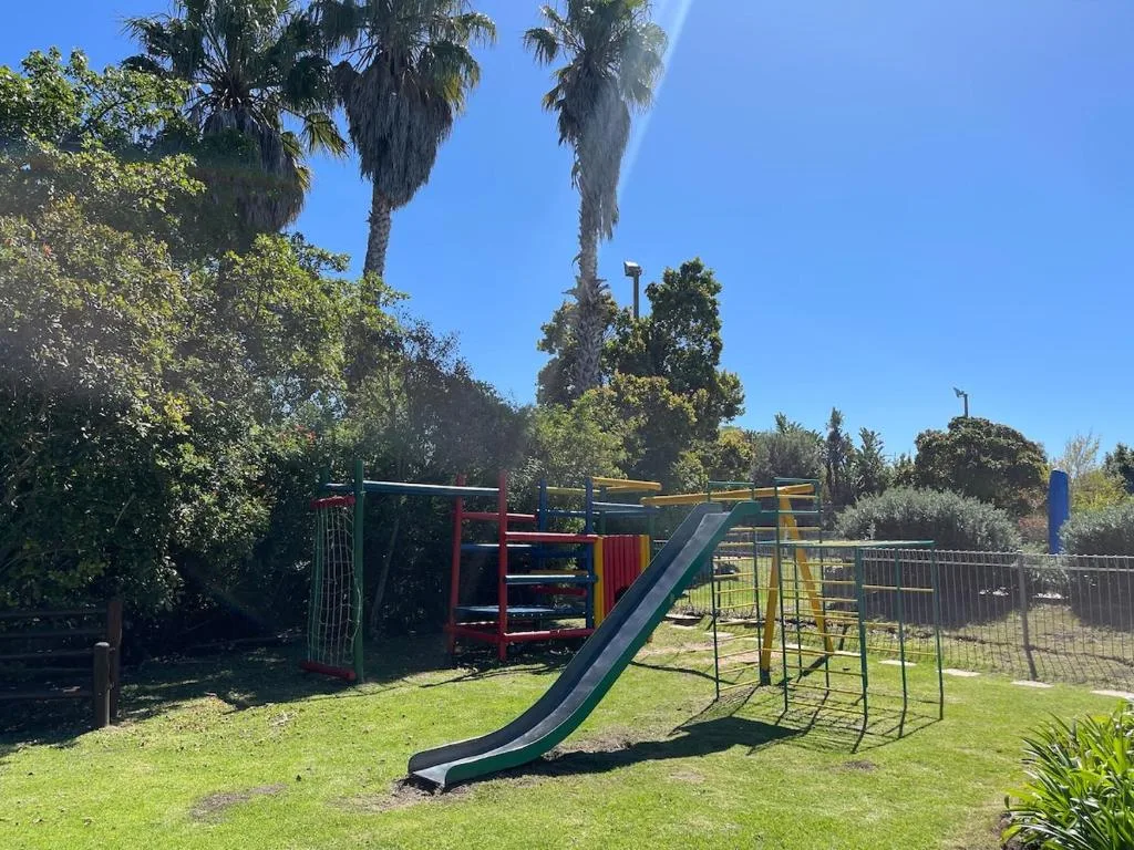 Children's playground with slide and climbing equipment on manicured garden lawn