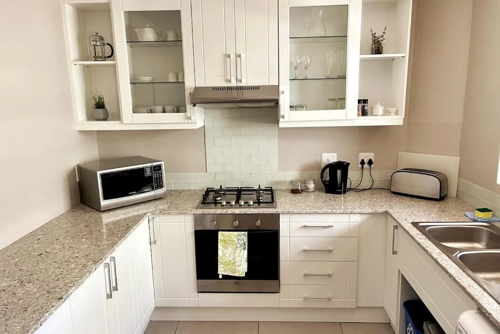 Modern white kitchen with granite counters, gas stove, and stainless steel appliances