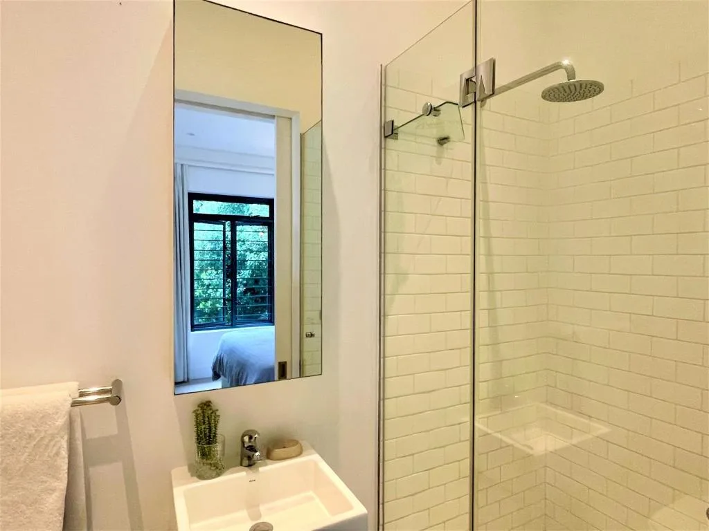 Modern bathroom with white subway tiles, glass shower enclosure, and mirror