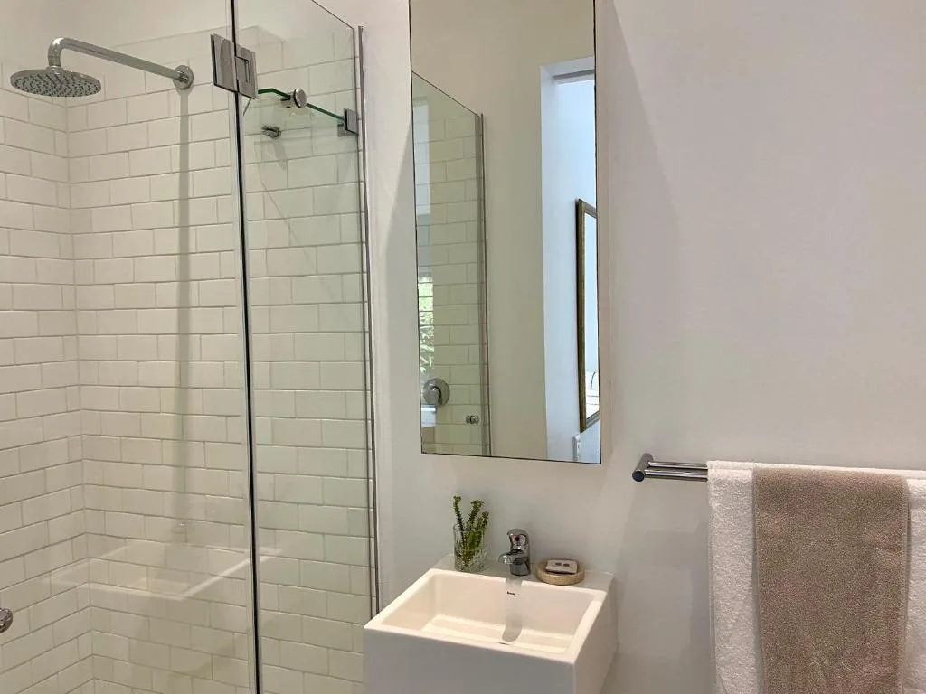 Modern bathroom with walk-in shower, white subway tiles, and vanity sink