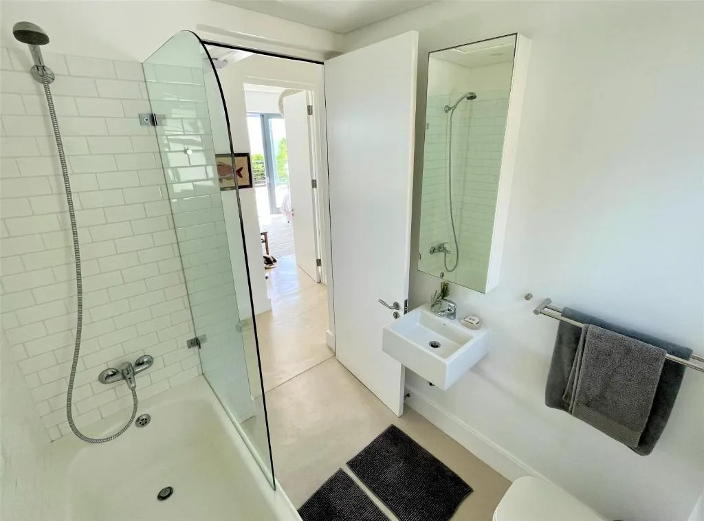 Modern bathroom with walk-in shower, white sink vanity, and mirror
