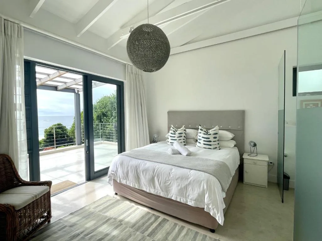Bright bedroom with ocean view through glass doors and modern pendant light