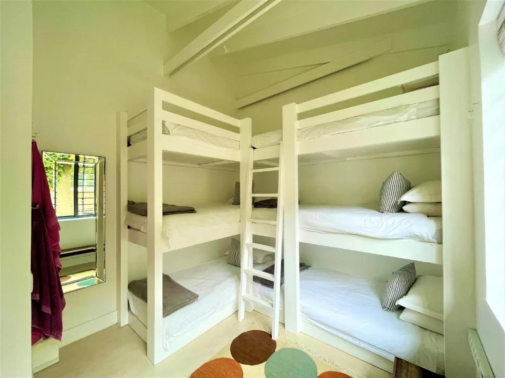 Bright dormitory-style bedroom with multiple white bunk beds and striped pillows
