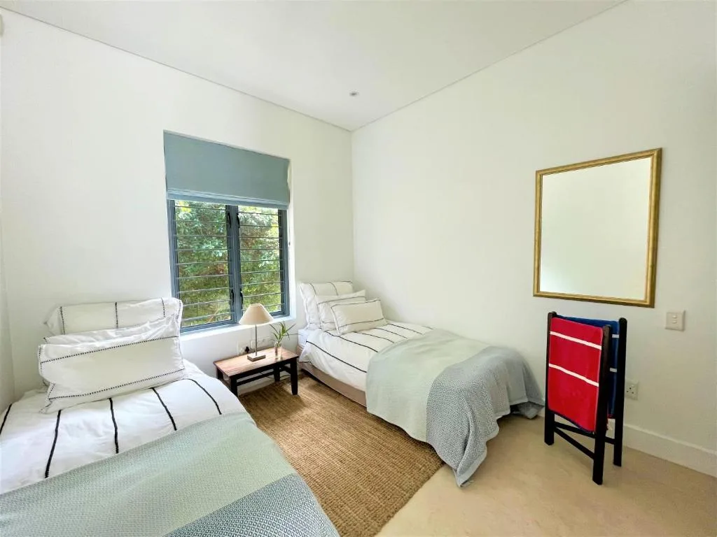 Bright bedroom with multiple beds and garden view through windows