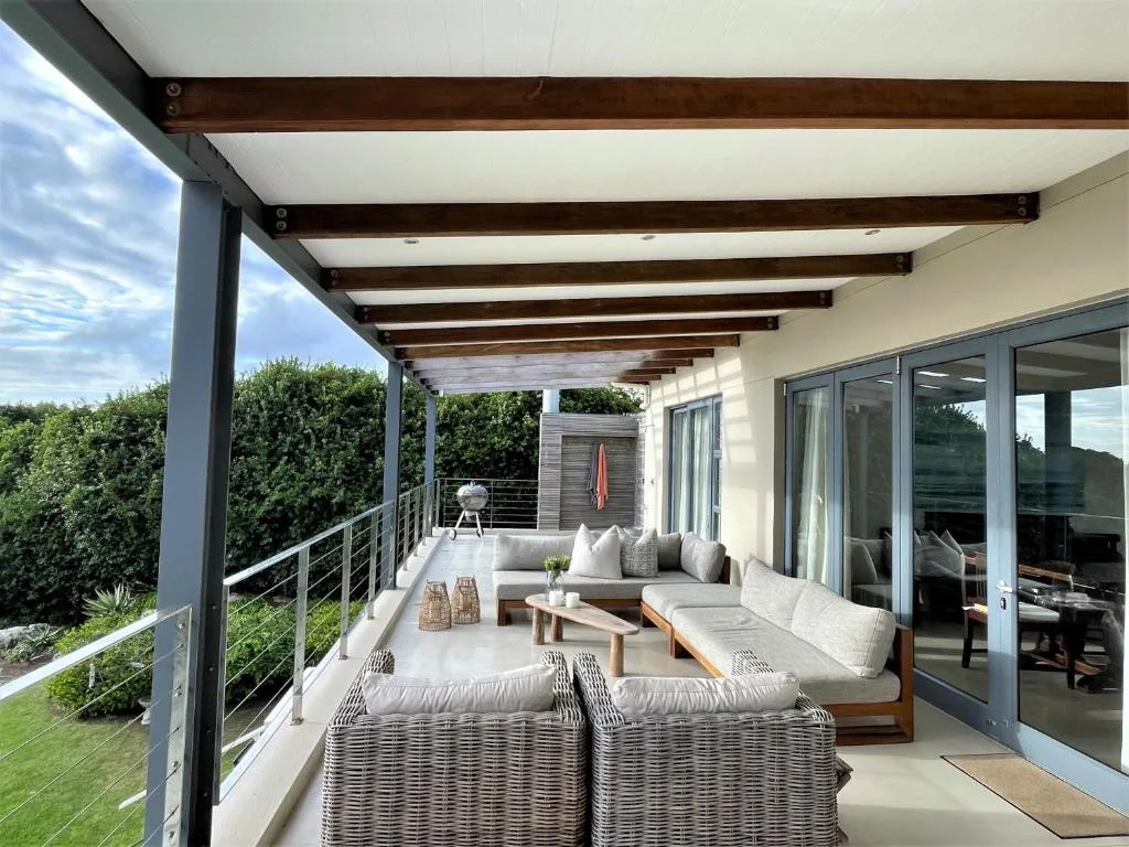 Spacious covered deck with modern seating and views over green landscape
